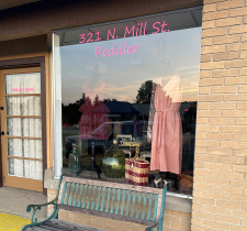 Vintage shopfront with dress display and glass decor.