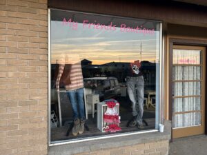 Storefront display with clothing and sunset reflection.